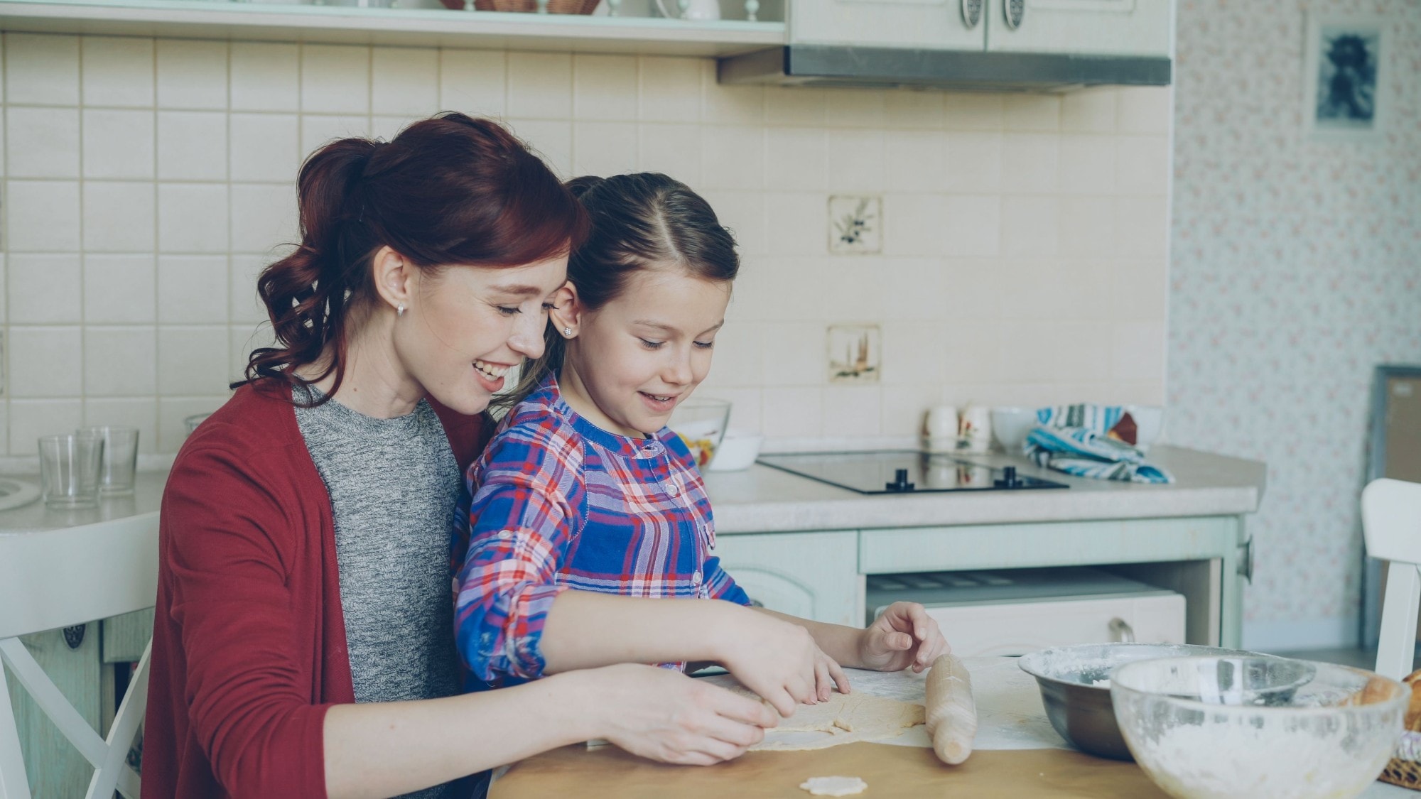 A teenager and a parent laughing together at a kitchen table with their phones put away