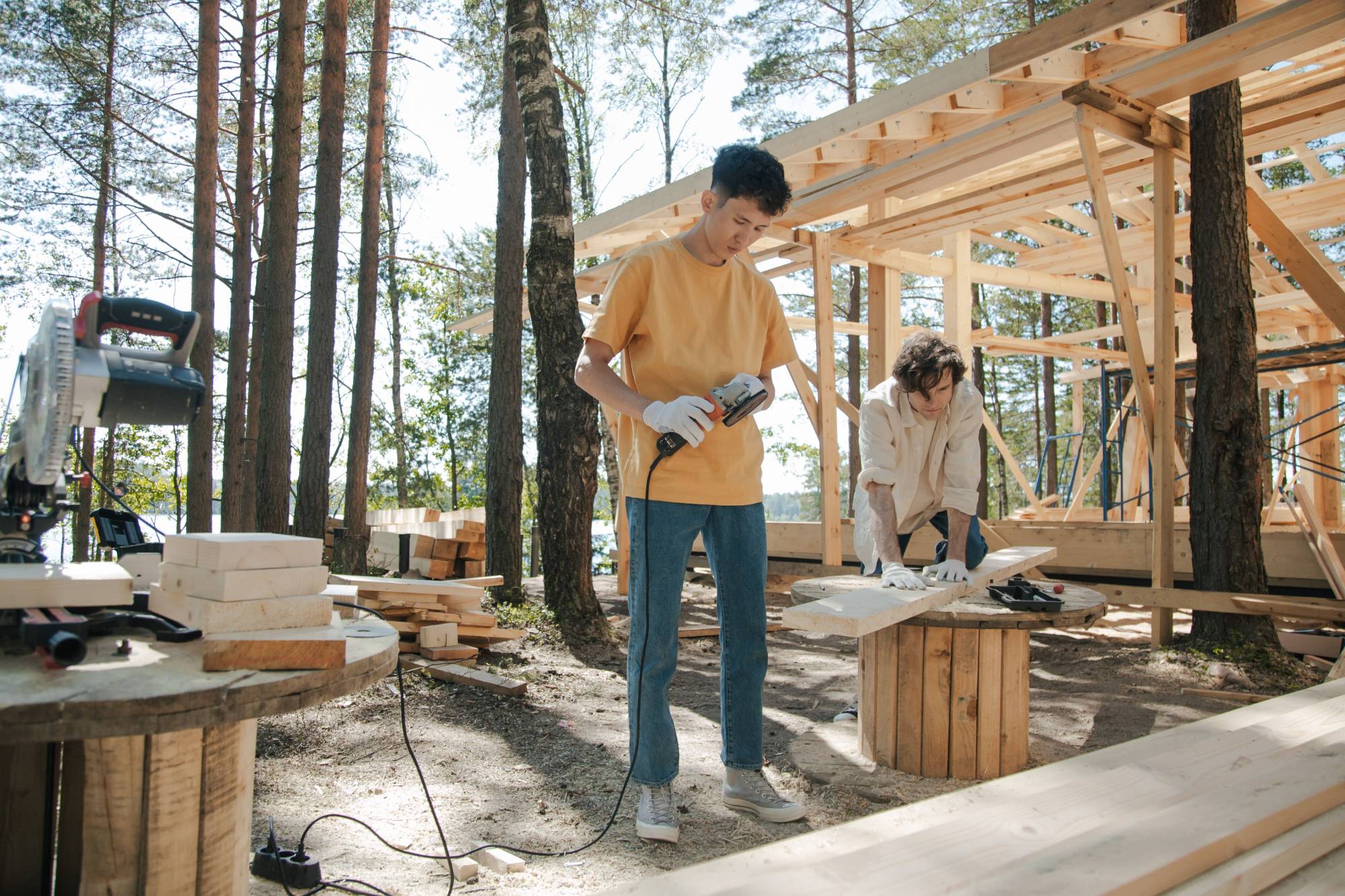 Two young men building a wooden structure together outdoors